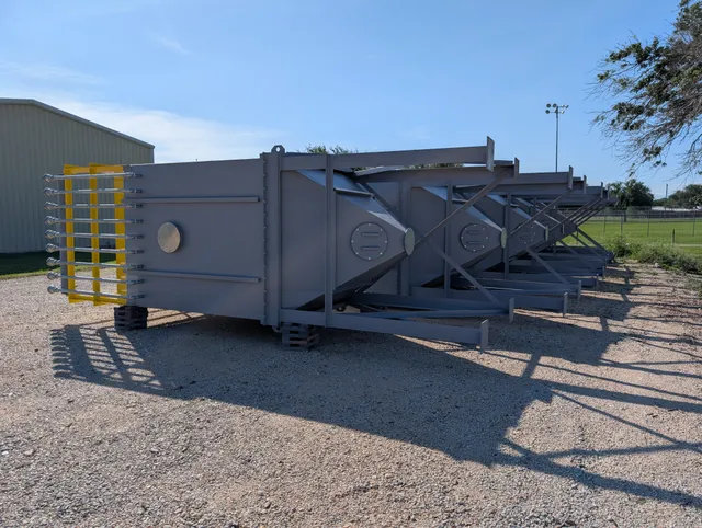 Row of fabricated dust collector housings lined up outdoors awaiting delivery