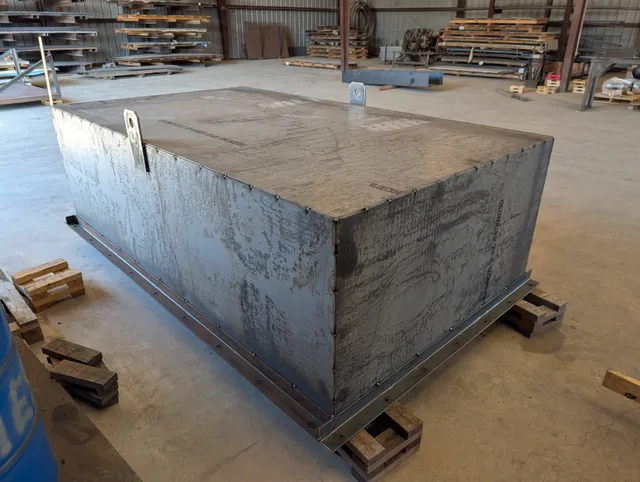 Heavy plate steel rectangular tank with welded seams on skid in the fabrication shop