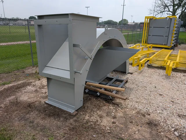 Primed gray centrifugal fan and housing assembly staged outside the shop